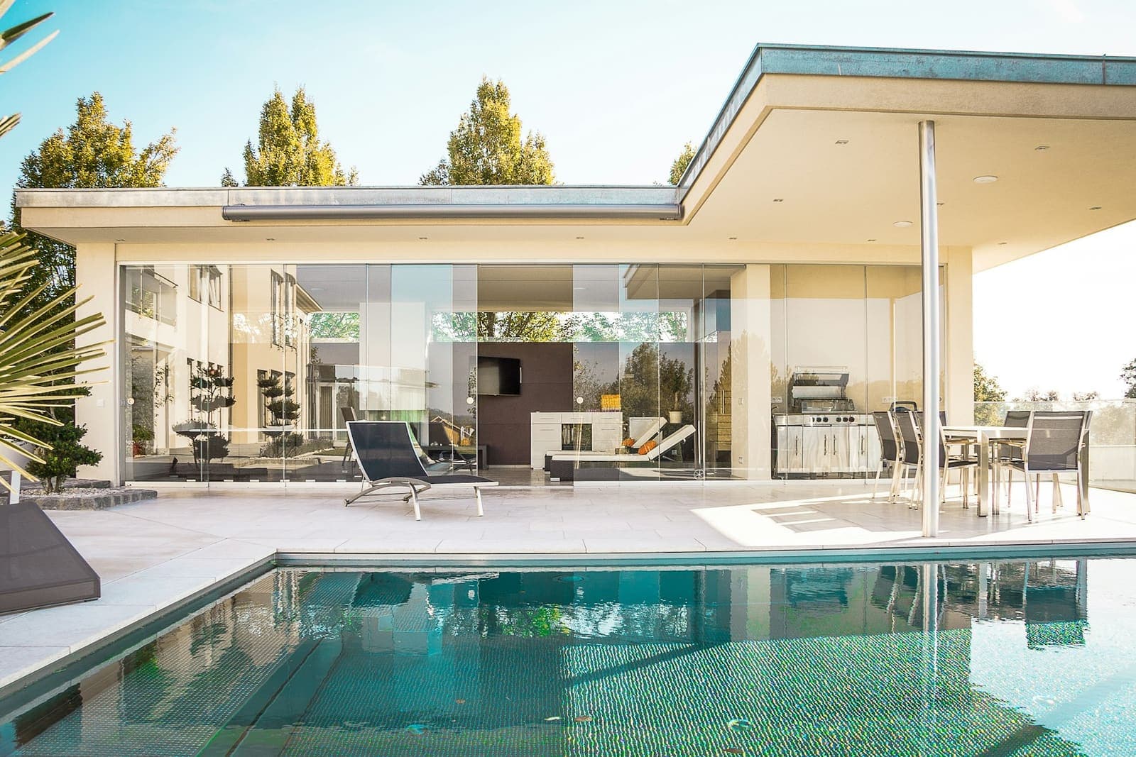 Glass-walled modern house beside a pool (placeholder stock photo)